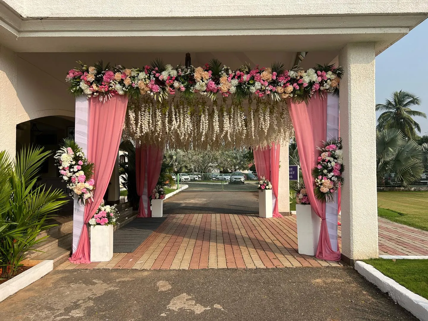 Pink wisteria daytime entrance arch with pastel florals and pink drapes