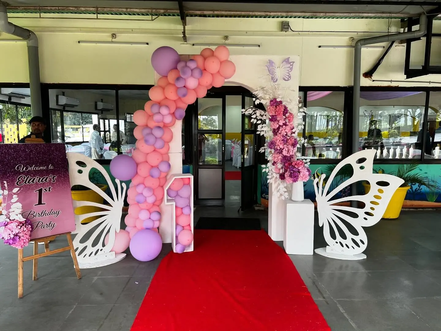 First birthday party décor with pink and lavender balloon arch and butterflies, by Imagine Decorators
